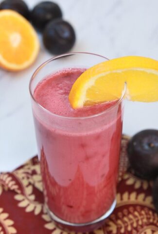 a glass ofPlum smoothie slice of orange on top