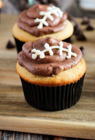 a cupcakes with chocolate frosting and footballs on a wooden board