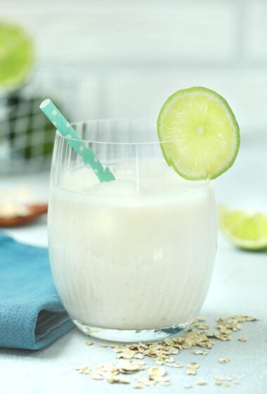 a refreshing glass of Jugo de Avena, garnished with a lime slice on the rim and a green polka-dotted straw.